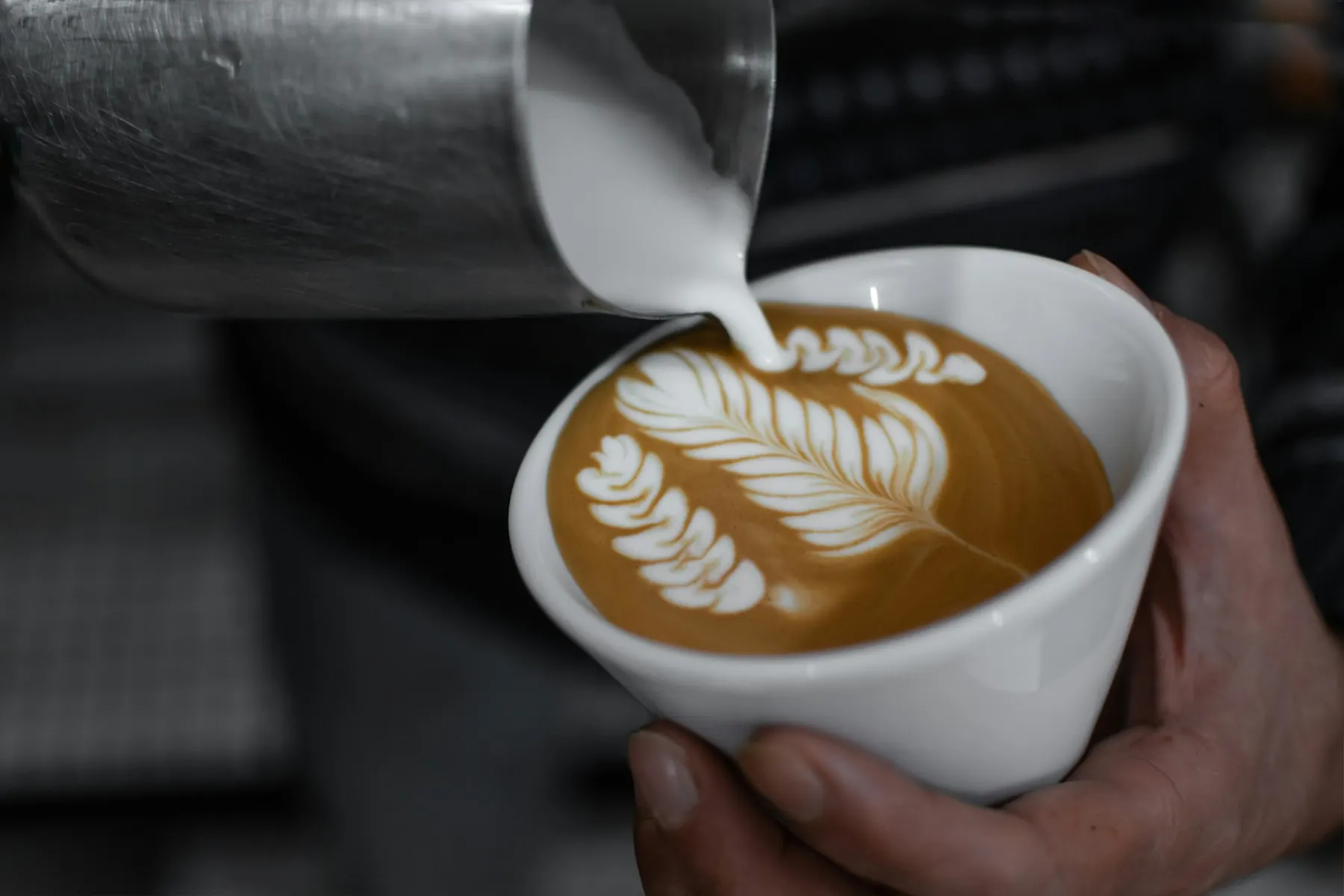 Barista ulijeva mlijeko u cappuccino
