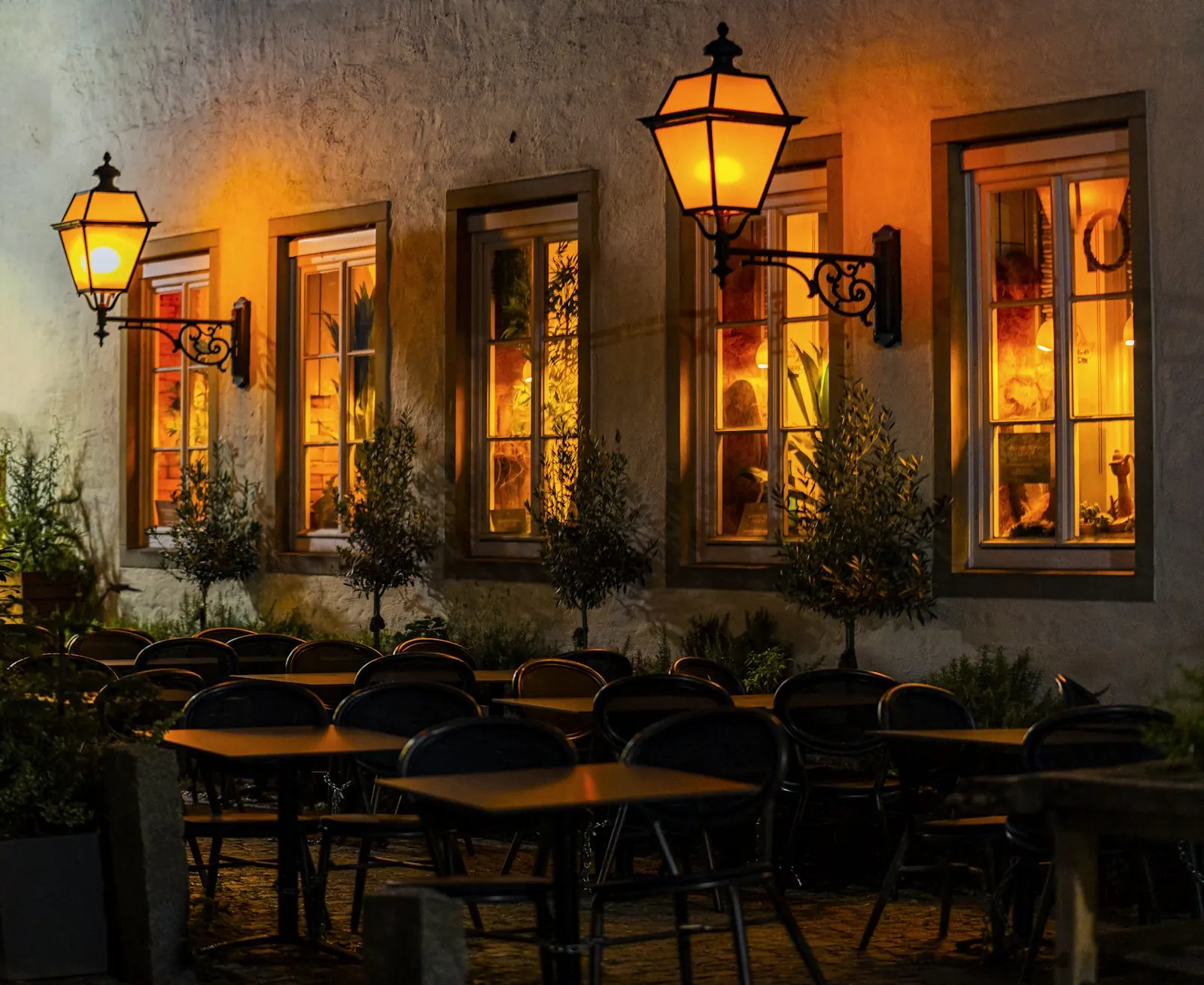 Terasa restorana navečer, stolovi pod uličnim svjetiljkama